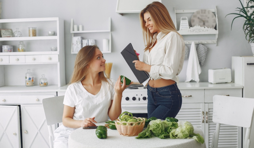 Beautiful and sporty girls in a kitchen with a vegetables
